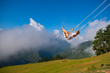 Girl swinging on a swing in the mountains of Georgia in Ushguli