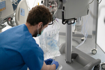 Male nurse preparing iv drip for patient in hospital room