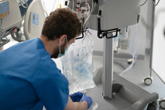 Male nurse preparing iv drip for patient in hospital room