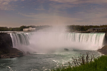 Fototapeta premium A dramatic view of Niagara Falls’ Horseshoe Falls, with turquoise water plunging into a misty abyss.