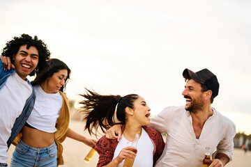 Group of young cheerful people having fun and drinking beer at the party on the beach looking happy, Enjoying youth and freedom concept