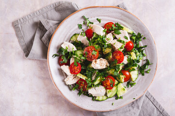 Close up of homemade salad with cucumber, tomatoes, chicken and herbs on a plate vertical view