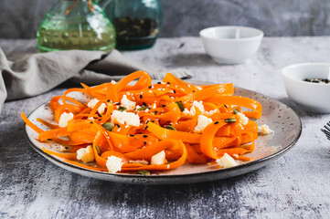 Spicy carrot, ricotta and pumpkin seed salad on a plate on a table
