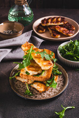 Grilled halloumi and arugula sandwich on a plate on a table vertical view