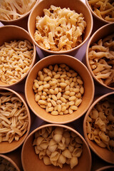 variety of raw pasta in a matching rustic bowls 