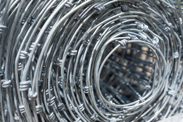 Detailed close-up of a tightly wound roll of galvanized wire mesh, highlighting the intricate...