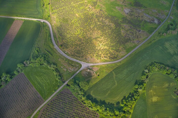 Winding roads through fields with sunrays, drone aerial view.