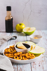 Delicious miso caramel dipping sauce, granny smith apples and pretzels on a plate vertical view