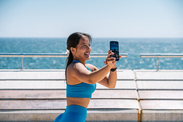 Woman taking selfie by the ocean on a sunny day