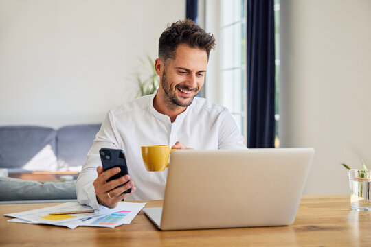 Man using laptop and mobile phone while working from home