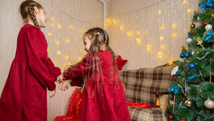 Happy positive kids have fun on Christmas day at home. Children dance to New Year music during winter holidays