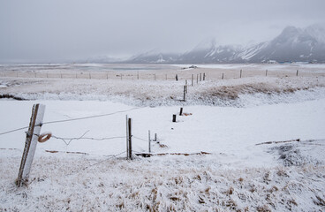Snow covering icelandic landscape with wire fence and mountains