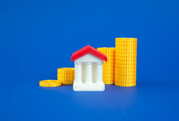 Stacks of coins in increasing order and a bank building. Growth of bank capitalization. Growth of savings in the bank account. Rising bank capitalization, deposit growth, increasing consumer savings.