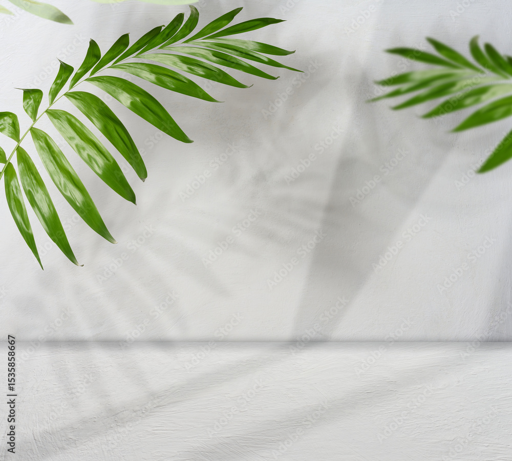 Poster green palm leaves on a light white wall and floor with falling shadows creating a natural background