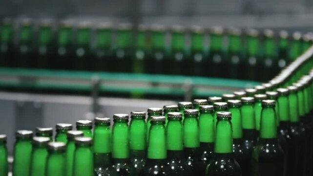 Glass beer bottles rolling smoothly along industrial conveyor belt, showcasing automated bottling process within modern brewery manufacturing facility