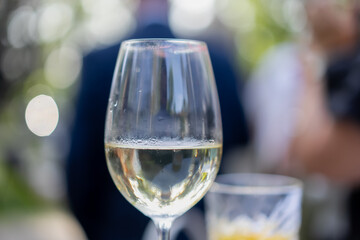 Obraz premium close up of white wine glass and cocktail on table at elegant outdoor event or wedding reception with guests in background, celebratory atmosphere with drinks, social gathering, summer party scene