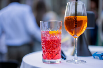 two colorful cocktails on white table at outdoor party or summer event, red drink in crystal glass...