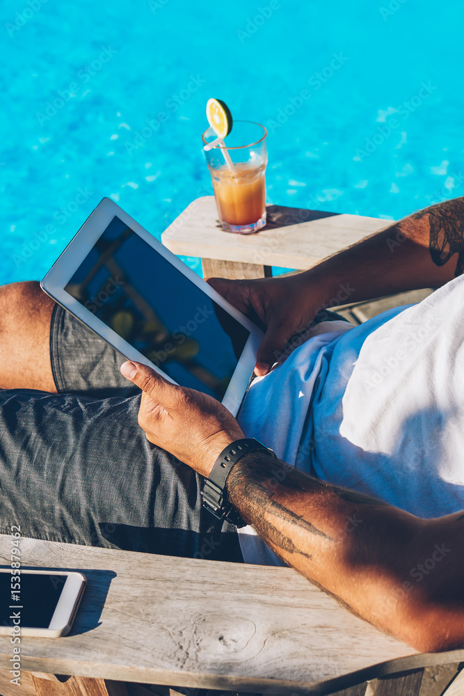 Poster bearded businessman in sunglasses resting on sunbed near blue pool enjoying summer time in luxury re