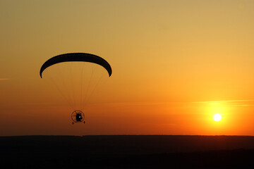 Sunset paramotoring adventure over serene landscape during golden hour