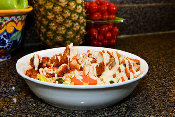A hearty white bowl filled with what appears to be a vibrant chicken and vegetable dish, possibly a deconstructed salad or a grain bowl, is prominently displayed on a dark, speckled countertop.