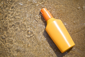 Tube of sunscreen on sandy beach top view. unbranded skincare bottle full of sunscreen for protection against ultraviolet radiation. Unbranded sunscreen bottle in sand during summertime. Sun cream.