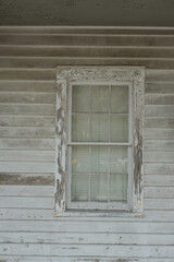 Fototapeta premium Abandoned old Wooden House with Boarded Windows Surrounded by Greenery. Weathered wooden house with boarded-up windows and signs of neglect, situated in a lush green environment. 