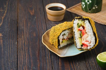 Fried sushi burgers in breading with crab sticks, cucumber and avocado filling on leaf-shaped plate on dark wooden background. Asian cuisine.