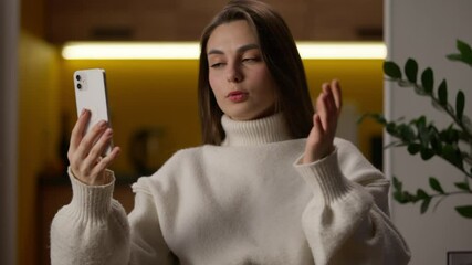 Caucasian woman holding mobile phone smartphone talking video call female online chat with friend young girl teen gesturing speaking chatting gadget blog blogger at home virtual meeting social media - Powered by Adobe