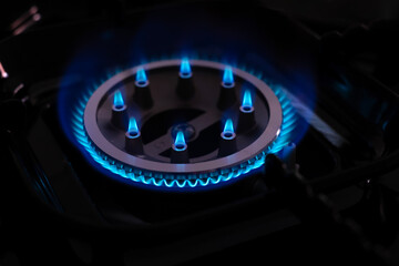 close up of a gas stove with blue gas flames from burning gas