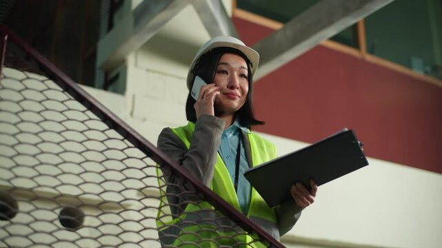 Korean Japanese businesswoman talking mobile phone cheking blueprint building builder project plan business woman female engineer Chinese Asian cheerful girl speaking smartphone contractor architect