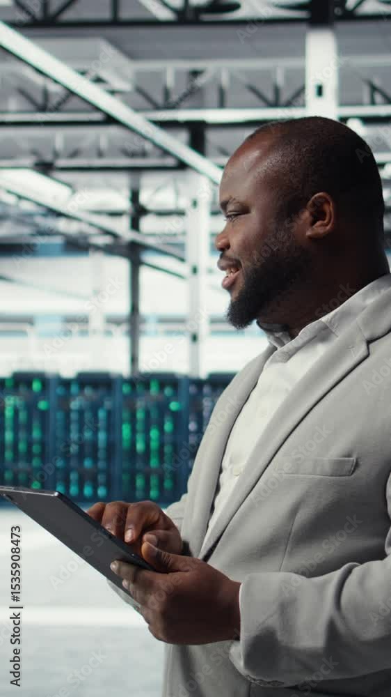 Poster vertical video engineer working in server farm using tablet to analyze data. it professional examini