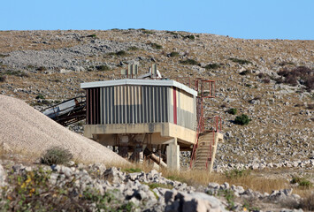 Large gravel sorting plant with metal conveyors, storage bins, and concrete walls stands in a...