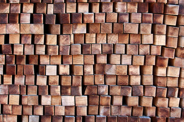 A large stack of square-cut wooden beams is arranged with the end grain facing outward, displaying...