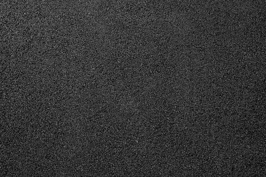 Close-up texture of smooth, freshly laid asphalt pavement with uniform dark gray color and fine