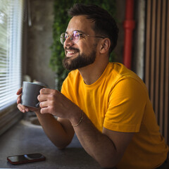cheerful adult caucasian man drink coffee in the kitchen