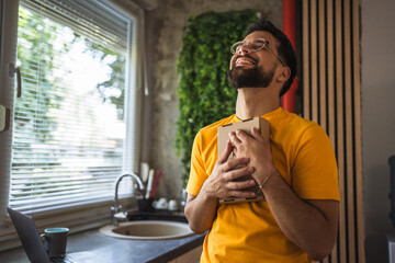Excited adult caucasian man embracing delivered box in the kitchen