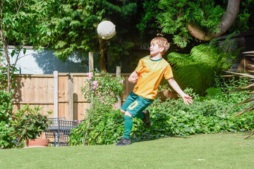 Boy playing football in a garden the child is practicing soccer skills