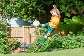 Boy playing football in a garden the child is practicing soccer skills