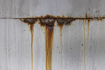 Close-up texture of aged gray metal with streaks of rust dripping down weathered surface
