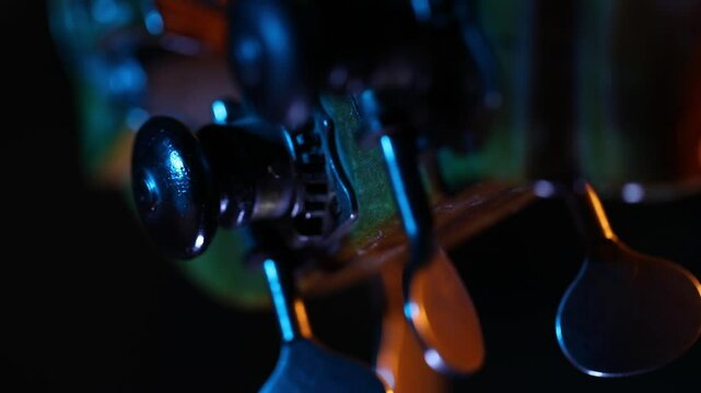A dramatic close-up rack focus reveals the wooden bridge and strings of a cello. Moody blue and orange light creates a cinematic atmosphere against a dark background.
