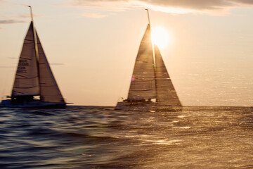 Sailing regatta in the Gulf of Finland at sunset, two sailing yachts competing in a race, splashing...