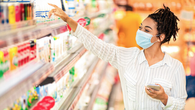 Grocery Shopping. African American Woman Wearing Protective Face Mask In Supermarket, Buying Food Products In Groceries Store Indoor. Female Buyer With Shop Cart In Hypermarket - Powered by Adobe
