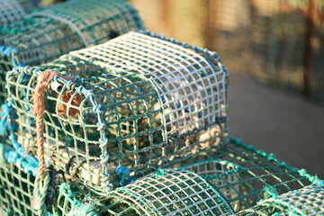 Crab traps are neatly stacked, showcasing their mesh structure and vibrant colors. The early...