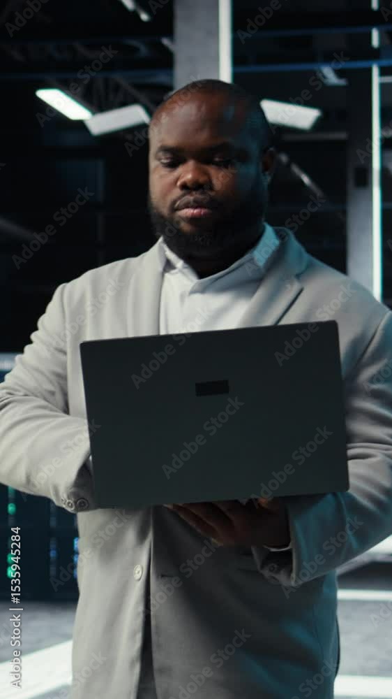 Poster vertical video data center admin coding, writing script on laptop, identifying bottlenecks. server f