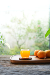 fresh oranges and orange juice on wooden tray by the window