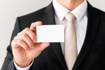 Businessman in formal suit holding a blank white business card, ideal for branding, identity presentation, or professional mock-up display
