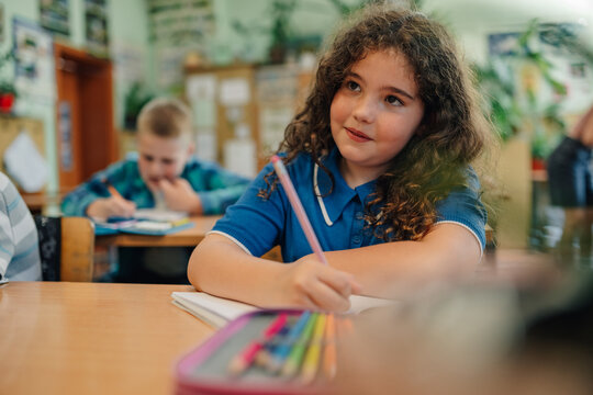 Elementary school student girl learning and thinking in classroom