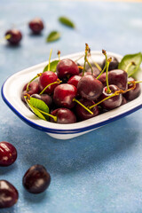 Fresh cherries fruits in a plate, blue background, copy space.