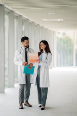 Doctors discussing medical chart in hospital corridor