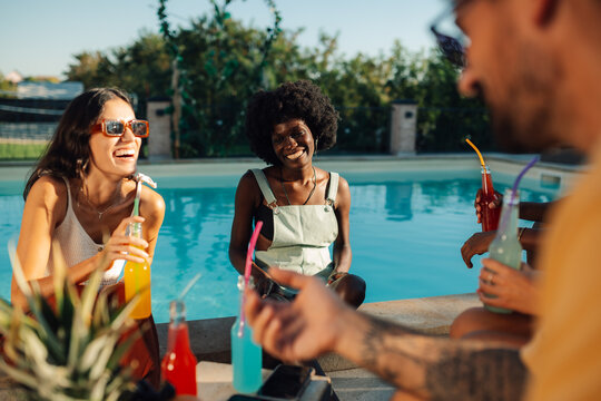 Friends enjoying refreshing drinks by the pool on a sunny day - Powered by Adobe